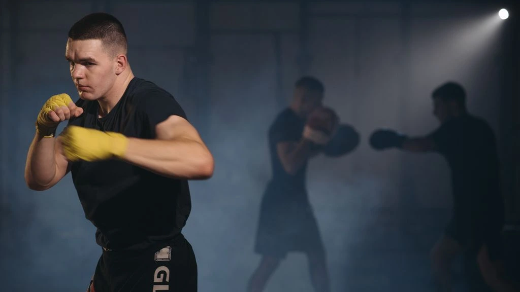 A fighter shadow-boxing alone in a dim concrete gym at dawn.